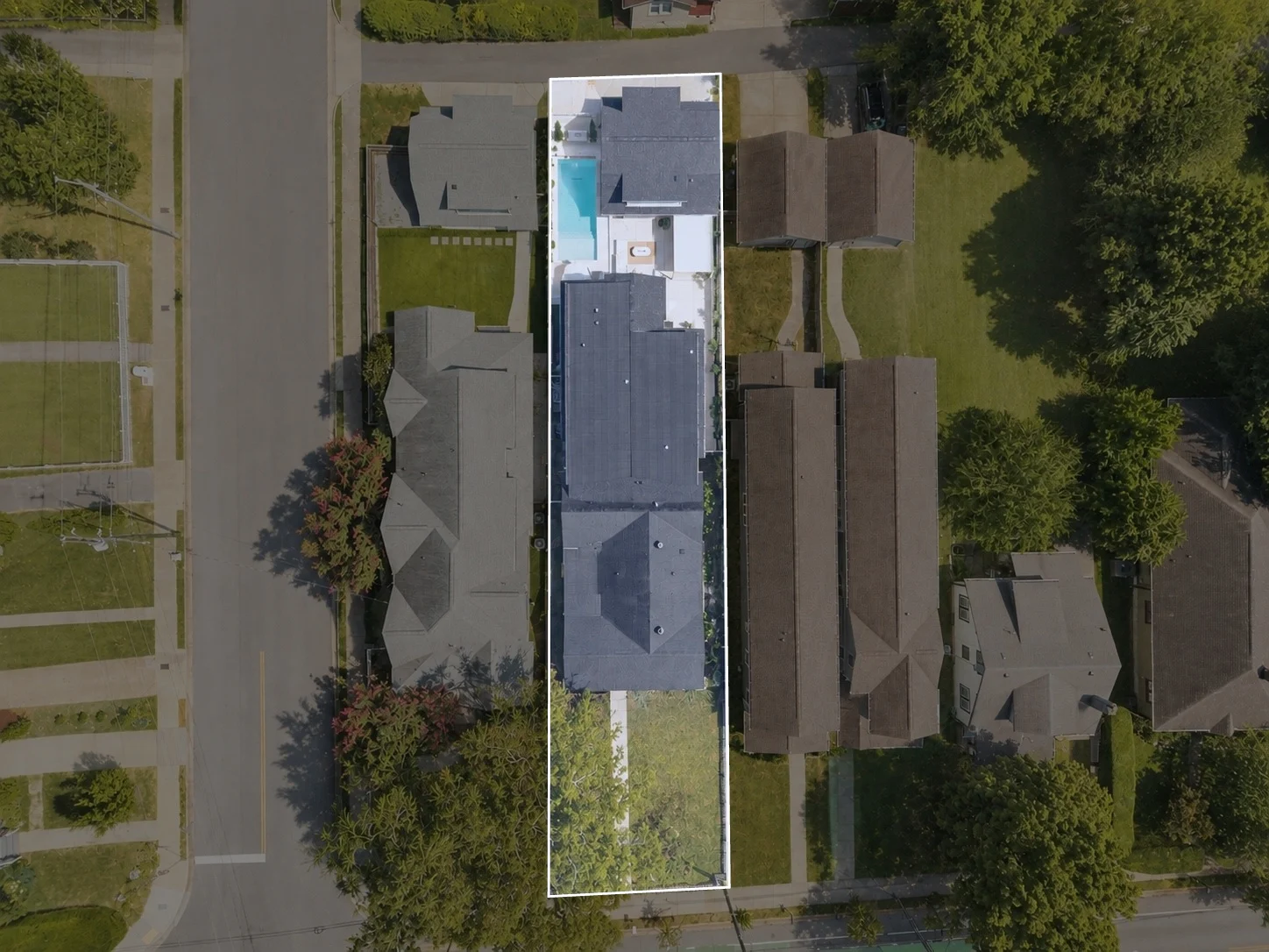 Aerial of the parcel: main house at the street, the saltwater pool and courtyard behind it, and the guest house above the garage at the rear