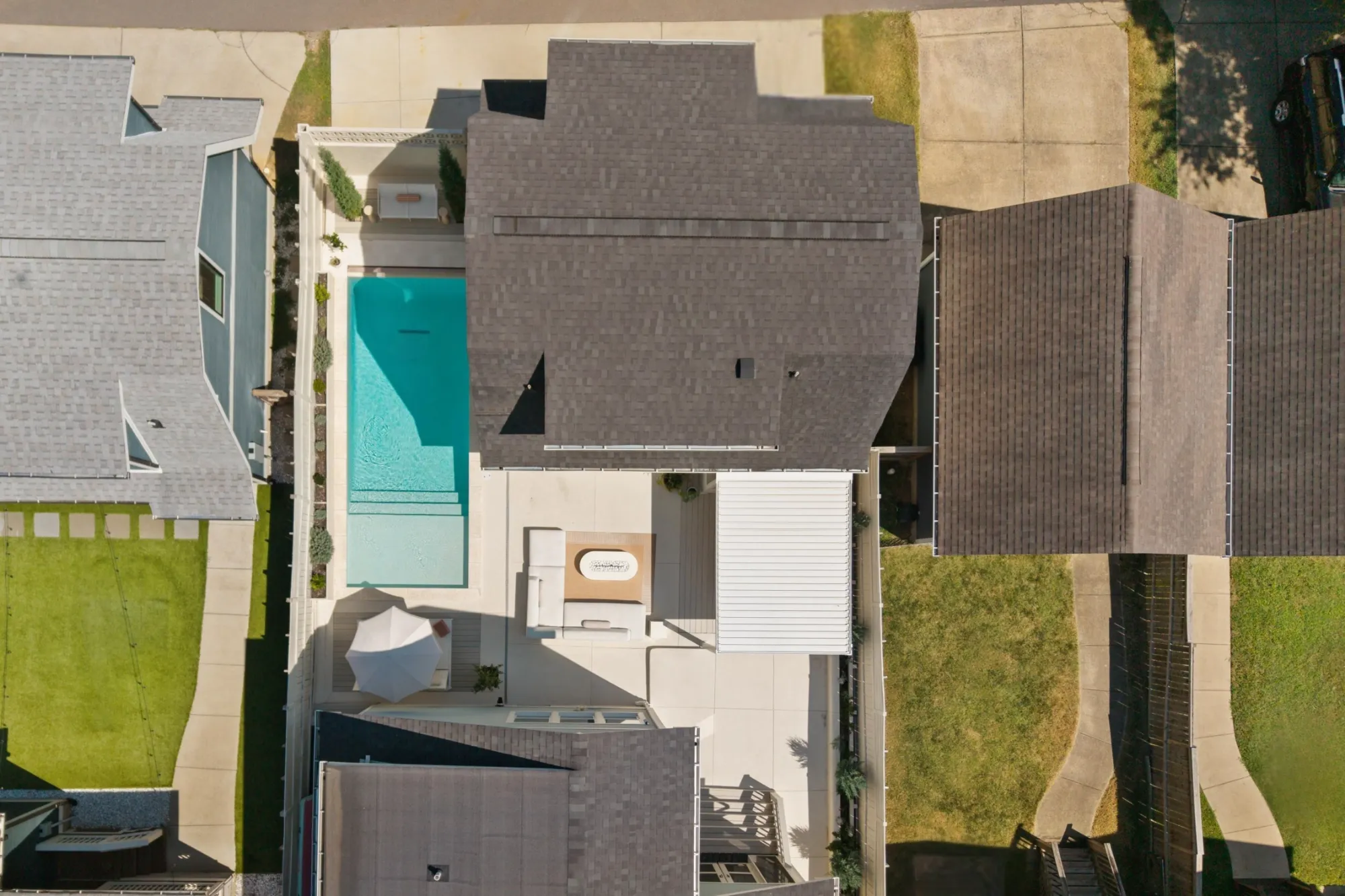 Straight-down view of the lot: the pool and courtyard between the main house and the guest house, with the putting green along the side