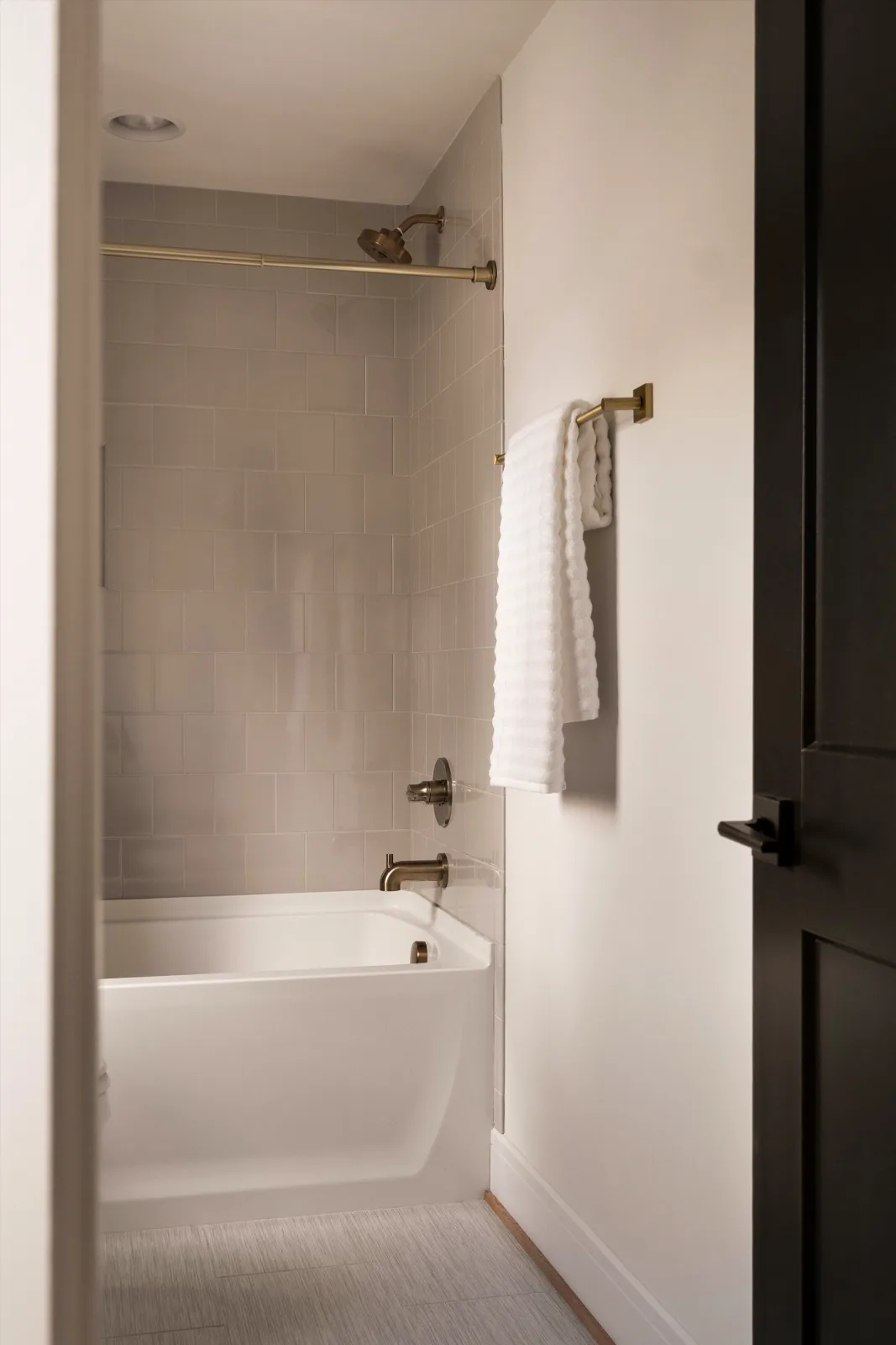 Its en-suite bath: tub and shower behind a brass rod, tile to the ceiling