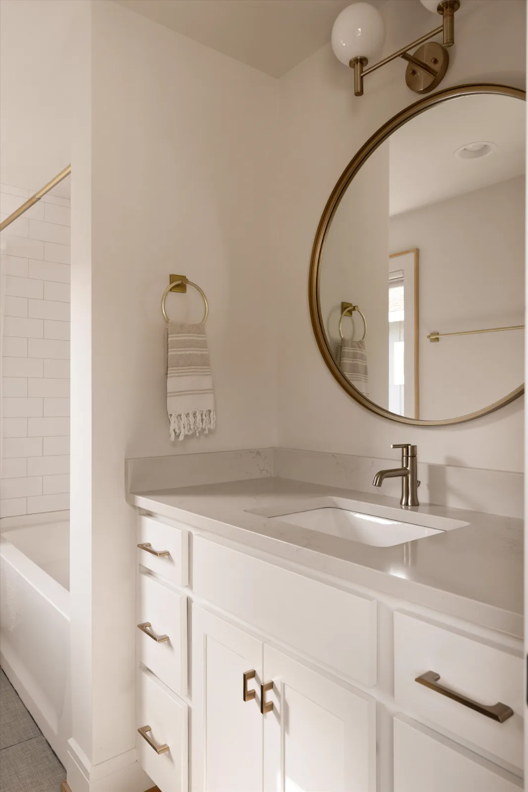 Its en-suite bath: vanity, round brass mirror and the tub beyond