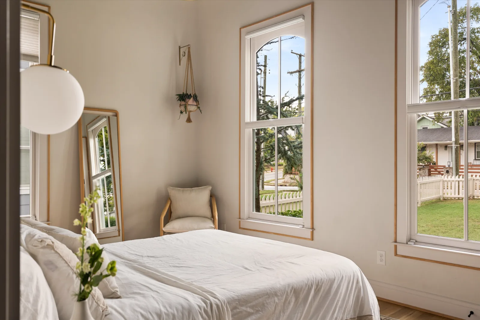 The same bedroom looking into the corner, with a reading chair between the two arched windows