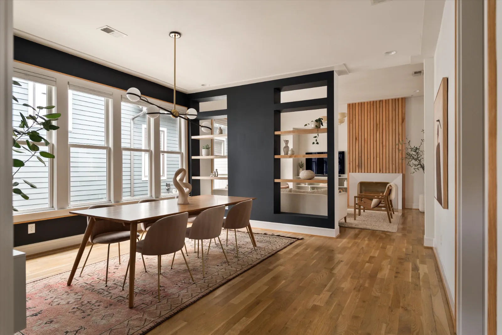 The dining room from the hallway: walnut table under a globe fixture, four tall windows along the left wall
