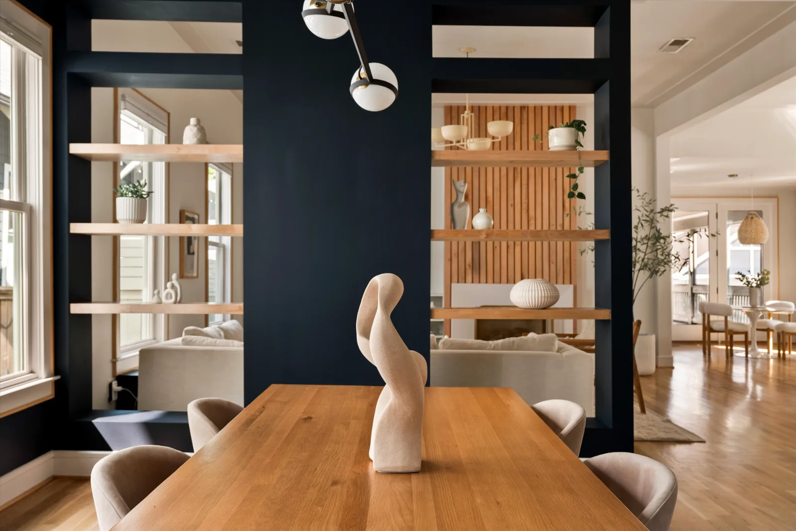 Through the partition of floating shelves to the living room, the slat wall and hearth beyond