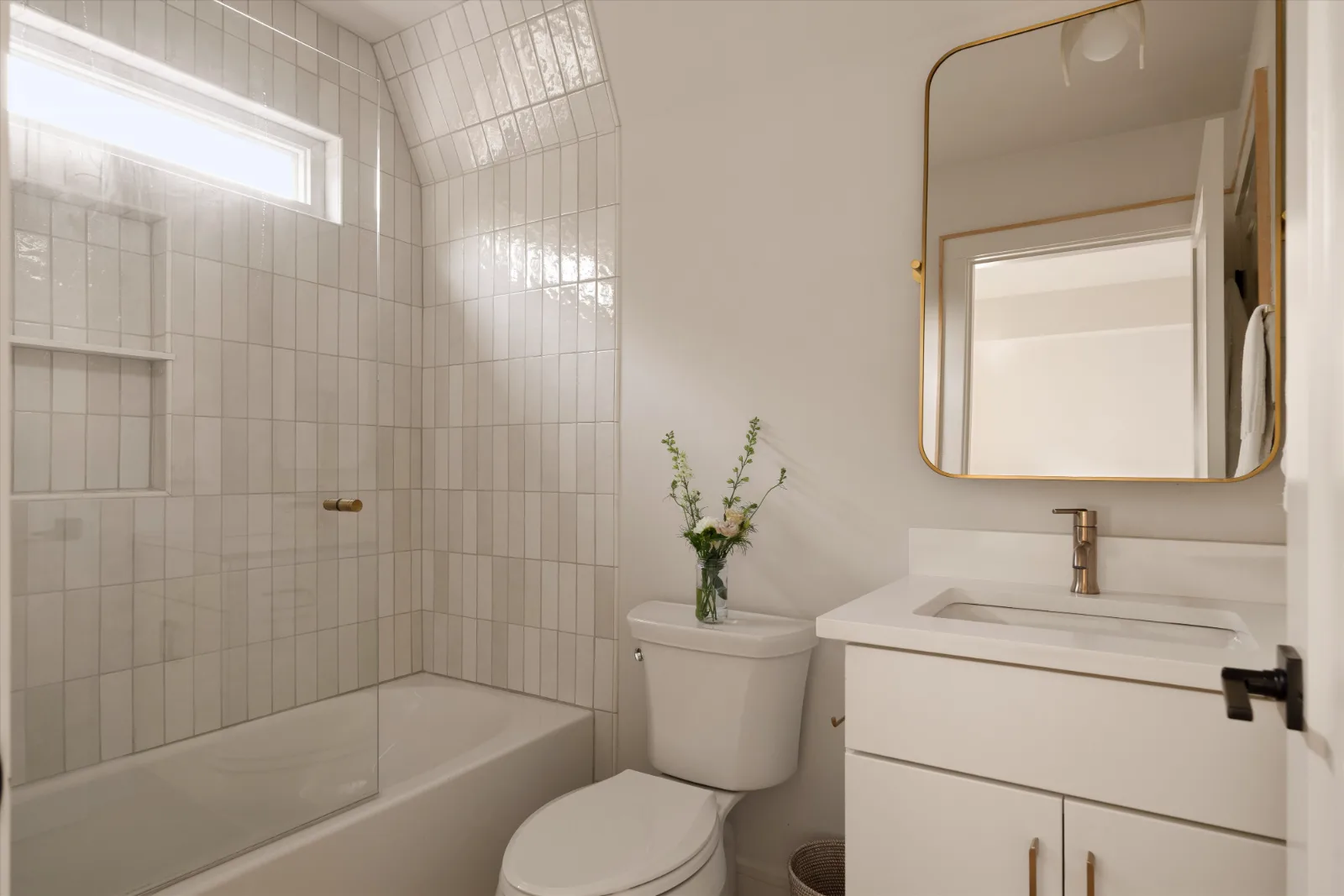 The guest suite bath: tub and shower behind glass, vanity and brass mirror