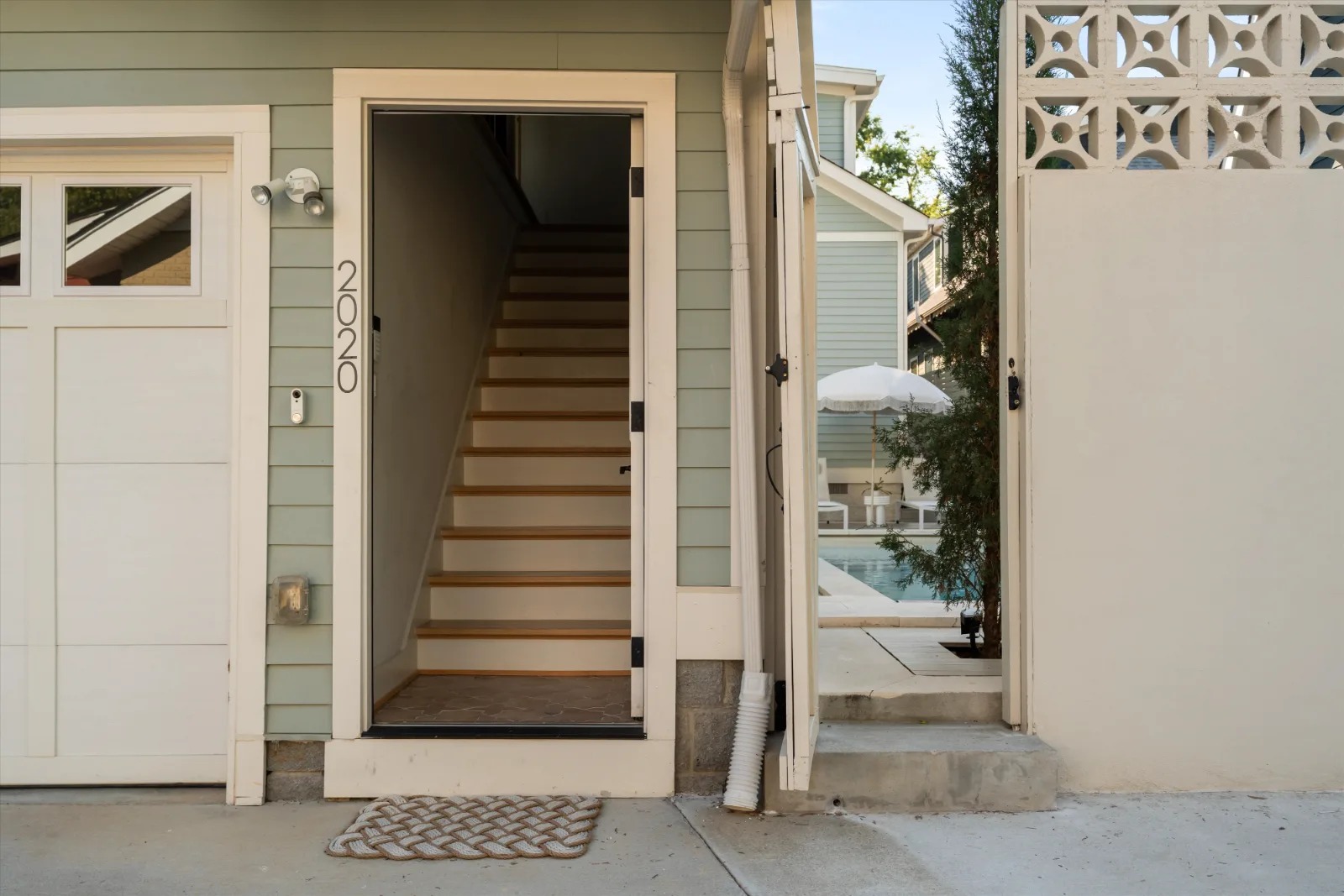 The guest house entrance: the house number on the jamb, stairs rising to the guest suite, and the pool through the gate