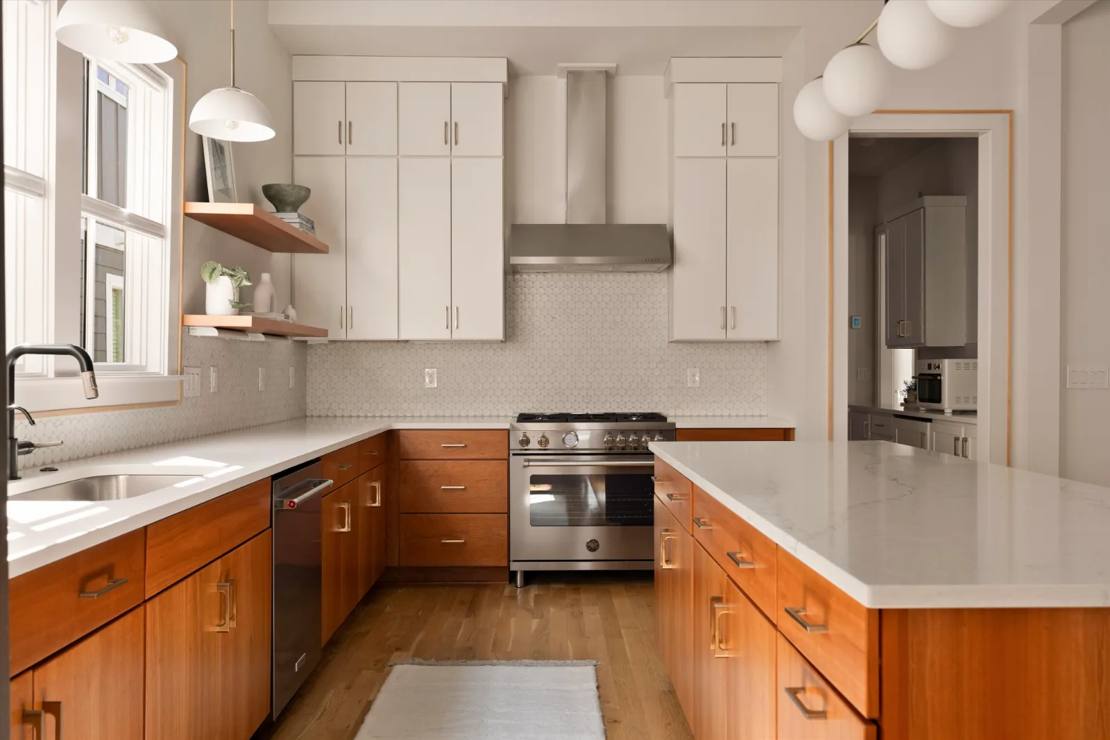 The kitchen: cherry cabinetry under a quartz top, round granite tile and floating shelves beside the range