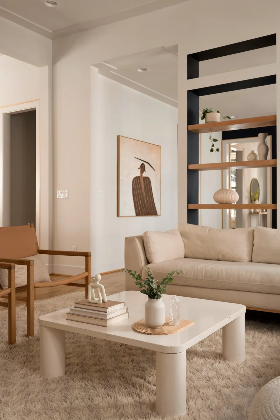 The living room: sofa and low table on a shag rug, with the shelving niche through to the dining room beyond