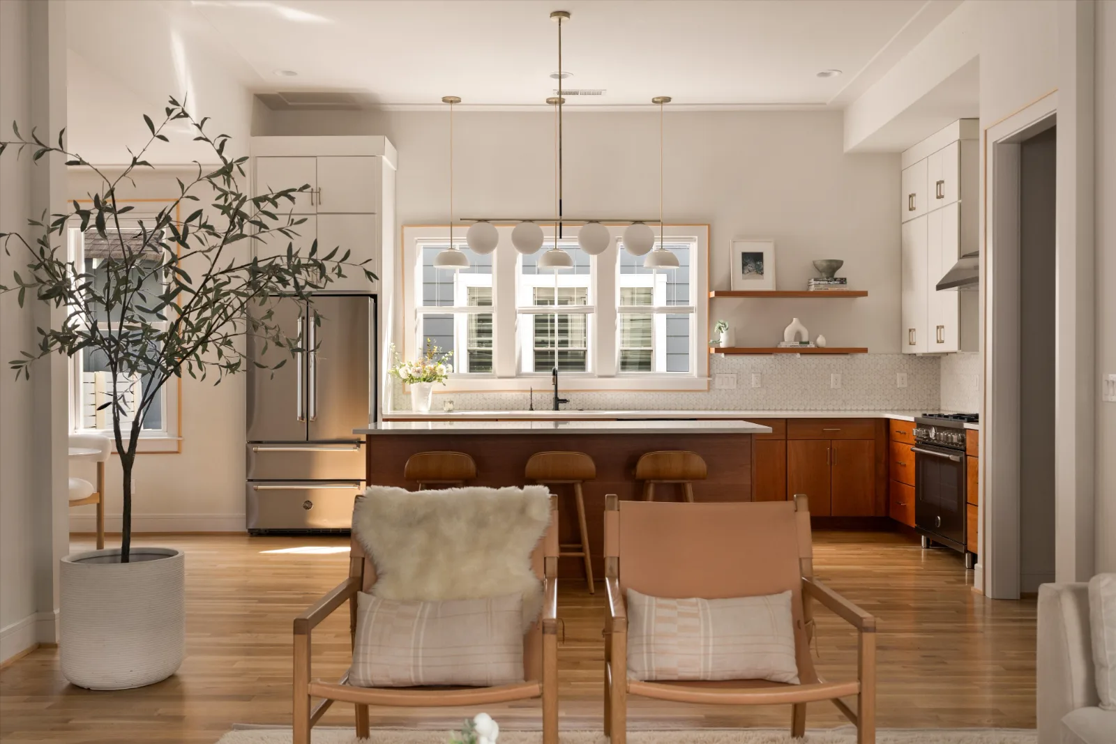 Looking across the living room to the kitchen island, range and window wall beyond