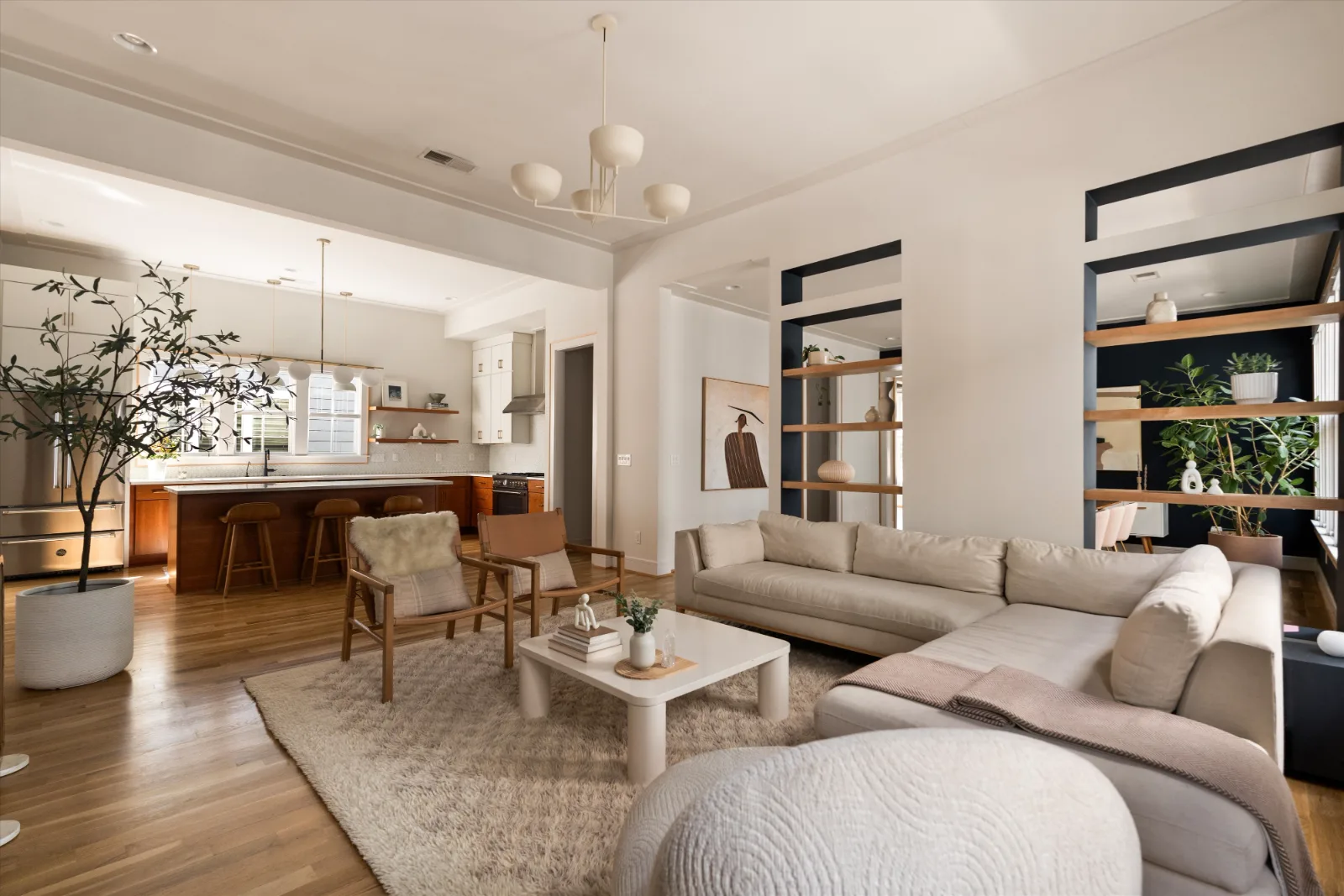 The living room open to the kitchen beyond, with shelving niches at right and the hearth at left