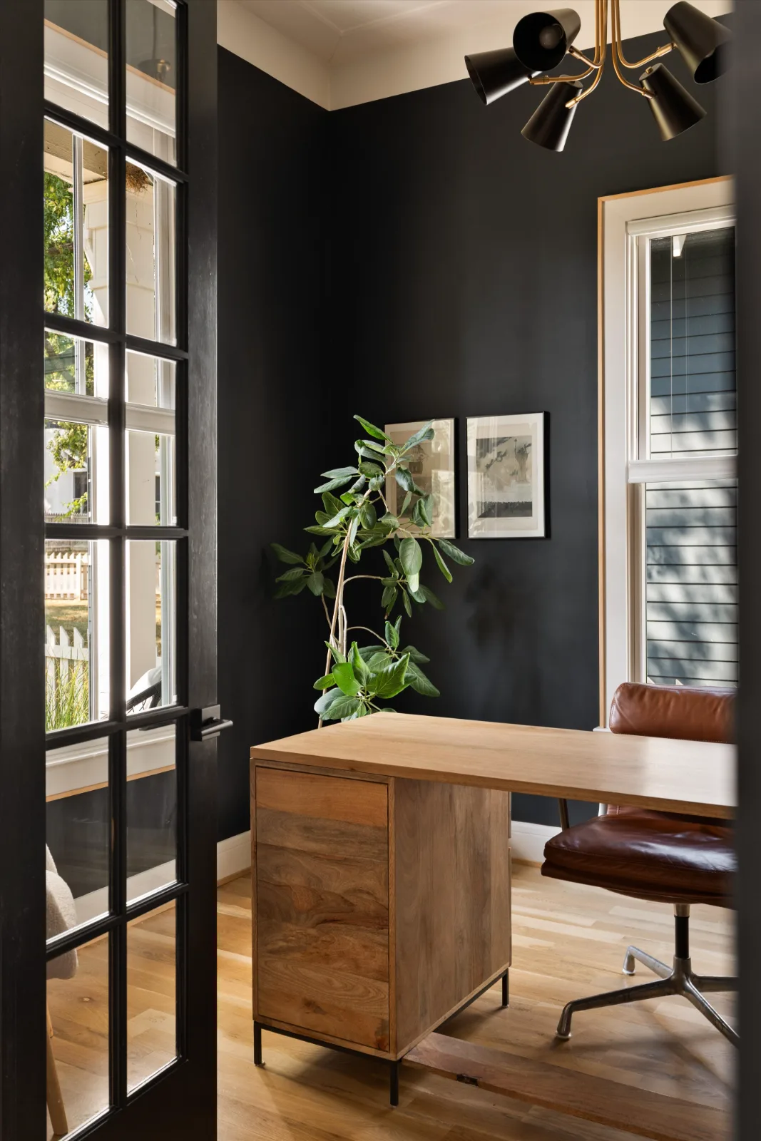The office seen through the open French door, with the chandelier and framed prints