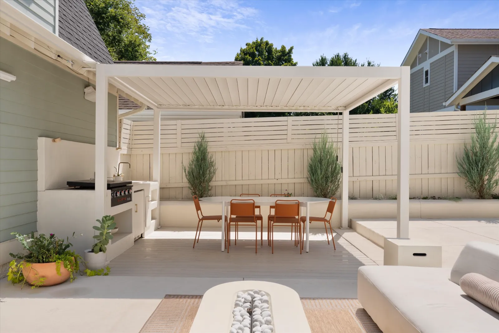 The louvered pergola over the outdoor kitchen and dining table, cypress in the raised beds along the garden wall