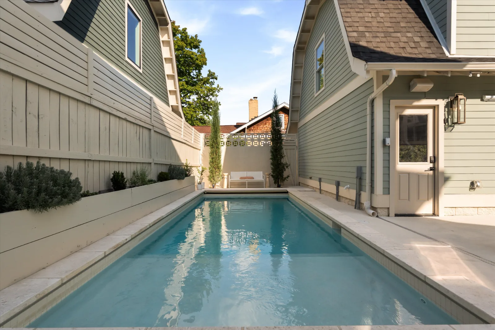 The pool down its length, lavender in the raised beds on one side and the guest house door on the other, the lounge seating at the far end