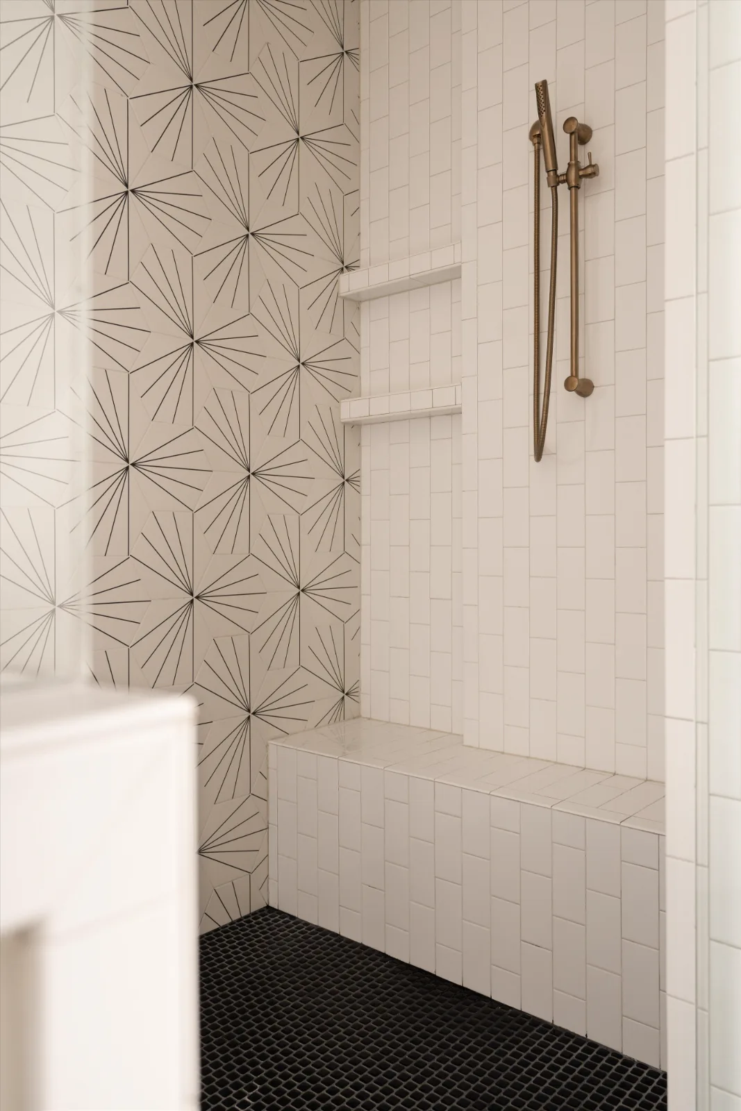 Freestanding tub under twin windows in the primary bath, on black hexagonal tile