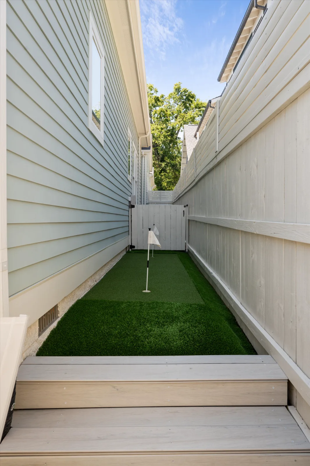 The putting green along the side yard, reached by steps from the courtyard deck